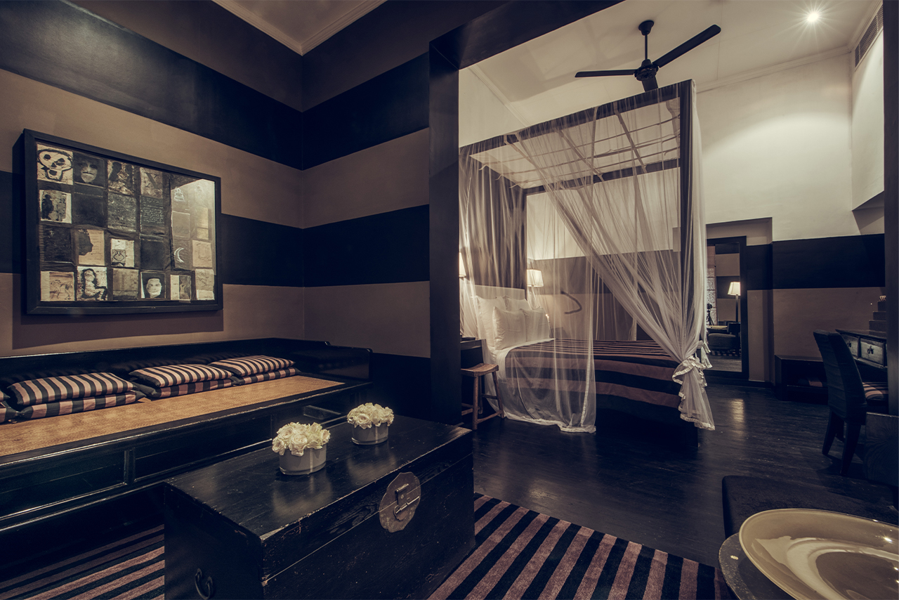 An Executive Suite, striped walls, a daybed and a four-poster bed hung with mosquito netting