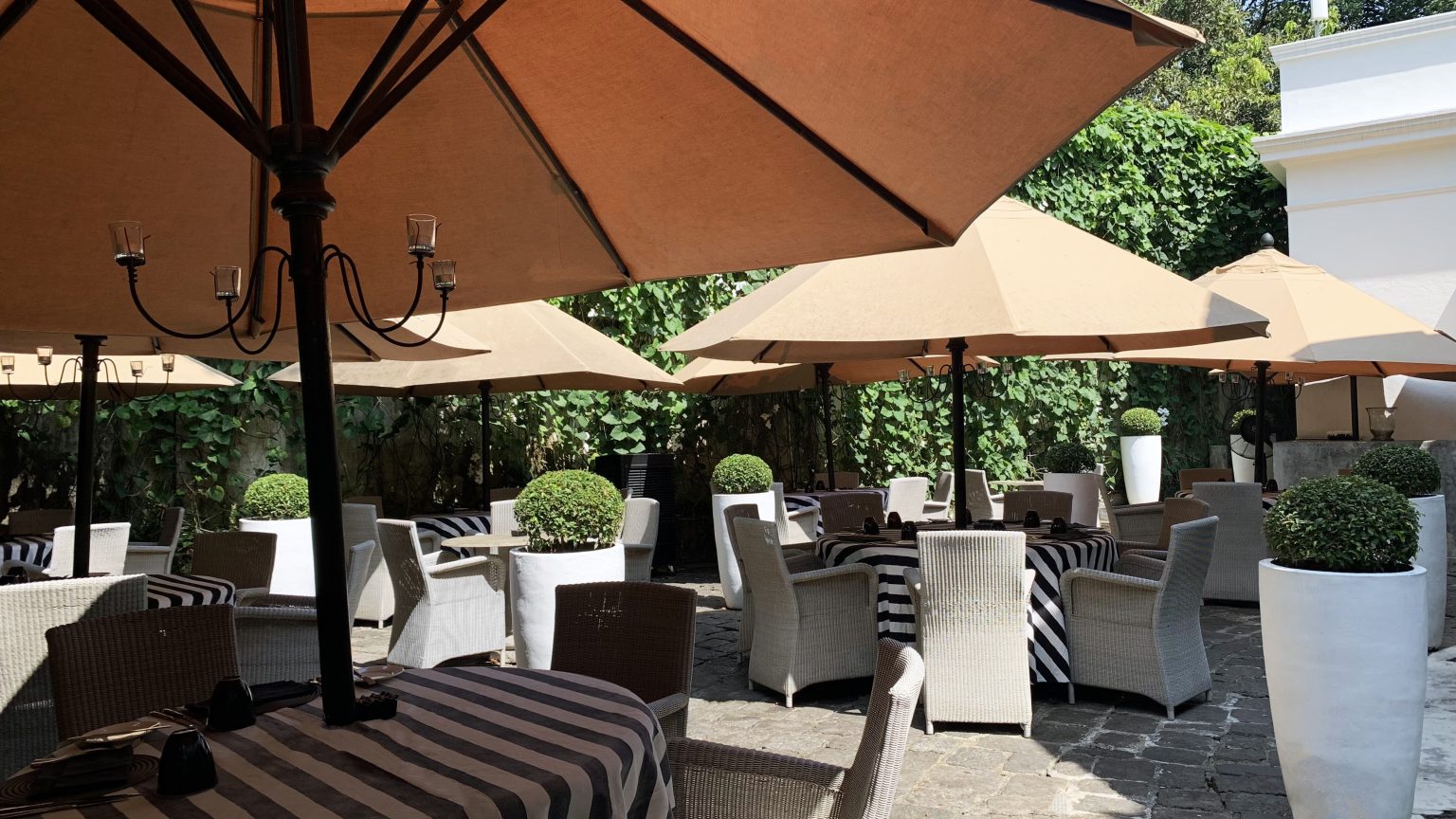 The courtyard restaurant, striped tables and white woven armchairs under parasols